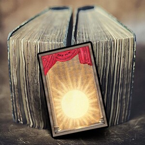 May include: A vintage illustration of the sun, with the text "THE SUN DIAMETER 882,000 MILES" in a red banner at the top. The illustration is framed in a black border and is set against a background of old, worn book pages.