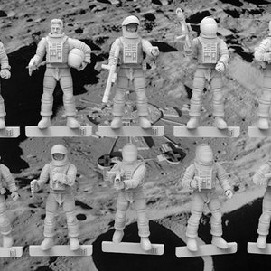 May include: A monochrome image featuring several miniature astronaut figures. Each figure is dressed in a spacesuit and helmet, with some holding weapons. They stand on rectangular bases, set against a backdrop depicting a lunar landscape.