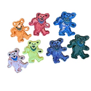 May include: Set of seven colorful enamel pins featuring a dancing bear design. The bears are in various colors, including orange, red, blue, yellow, pink, purple, and green.