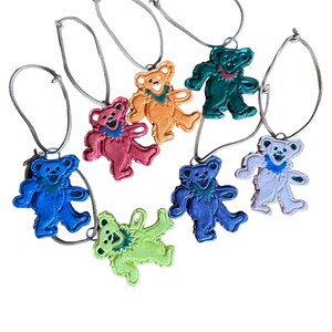 May include: Set of seven colorful ceramic bear ornaments with a tie-dye pattern. Each bear is attached to a brown string for hanging.