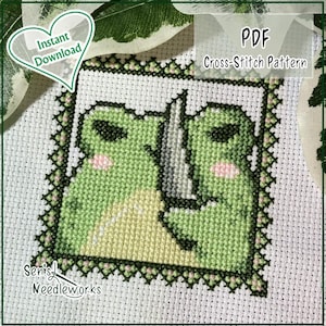 May include: Cross-stitch pattern of two green frogs with a knife, on white fabric. The design has pink cheeks and black outlines. Text includes "PDF Cross-Stitch Pattern" and "Instant Download". The artist's name is "Senis Needleworks".