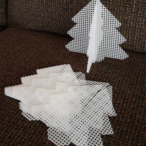 May include: A set of white plastic pieces that can be assembled into a 3D Christmas tree. The pieces are shaped like triangles and have a grid pattern.