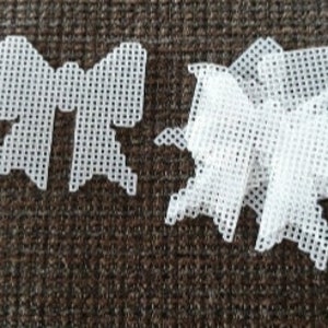 May include: Two white plastic craft shapes, one a bow and the other a butterfly, on a brown surface.