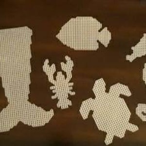 May include: Five white plastic canvas patterns of sea creatures: a mermaid tail, a fish, a seahorse, a crab, and a turtle.