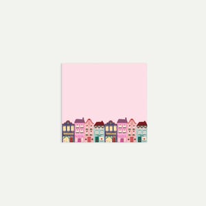 May include: A pink square notepad featuring a row of illustrated houses at the bottom. The houses are in various colours, including purple, pink, blue, and green, with detailed windows and doors. The background is a solid light pink.