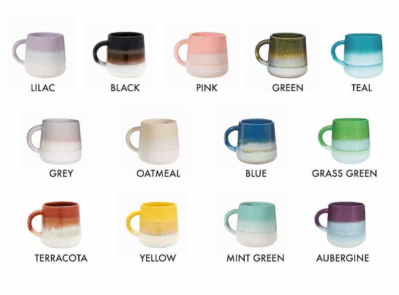 May include: Twelve ceramic mugs in various colors, each with a gradient glaze effect. The mugs are arranged in four rows of three, with the colors of the mugs in each row being similar. The colors of the mugs are lilac, black, pink, green, teal, grey, oatmeal, blue, grass green, terracotta, yellow, mint green, and aubergine.