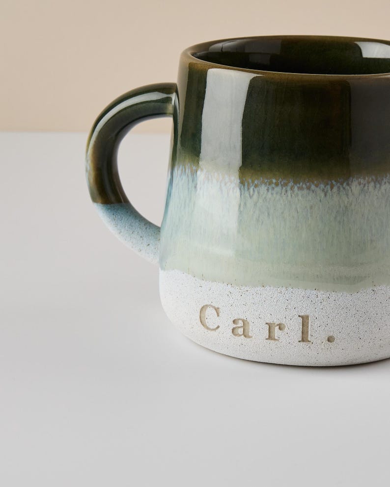 May include: A green and white ceramic mug with a handle. The mug has a gradient of green to white and is personalized with the name "Carl."