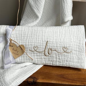 Envolver al bebé con el nombre y corazones. Regalo de maternidad único bordado en tela hidrófila