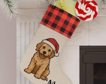 Op de afbeelding: Een beige kerstsok met een rode en zwarte buffelruitmanchet. De sok heeft een cartoonillustratie van een goudkleurige hond met een kerstmuts, met de naam "Max" in zwart schrift. Een rood-witte swirl lolly is bevestigd.