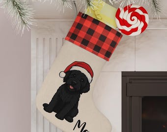 Op de afbeelding: Een kerstsok met een zwarte hond met een kerstmuts. De sok heeft een rood-zwarte buffelruitmanchet en de naam "Max" erop gedrukt. Een rood-witte swirl lolly is bevestigd.