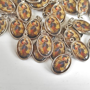 May include: A group of silver oval-shaped charms with a religious image of a woman holding a rope. The charms have a silver loop for attaching to a chain or bracelet.