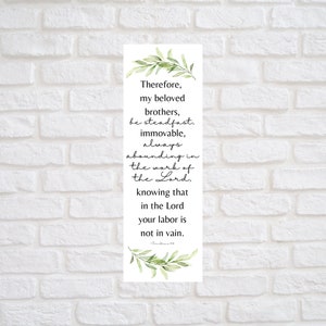 Puede incluir: Un fondo blanco con textura de pared de ladrillo. Un cartel vertical con un borde de hojas verdes y una cita bíblica en texto negro: «Por tanto, hermanos míos amados, estad firmes, inamovibles, abundando siempre en la obra del Señor, sabiendo que vuestro trabajo en el Señor no es en vano.» El texto es de 1 Corintios 15:58.
