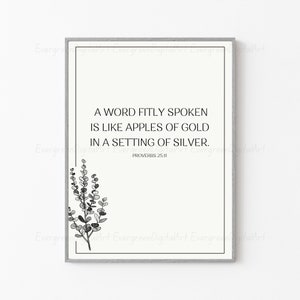 Può includere: Arte da parete stampabile in bianco e nero con una citazione da Proverbi 25:11, "Una parola detta a tempo è come mele d'oro in un'impostazione d'argento." La citazione è circondata da un semplice design floreale in bianco e nero.