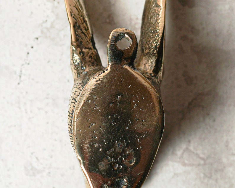 May include: A brass wall hook shaped like a bird with its wings spread out. The hook is designed to be mounted on a wall and has a small hole at the top for hanging.