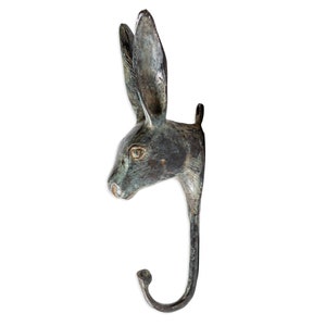 May include: A bronze rabbit head wall hook with a green patina finish. The hook is shaped like a rabbit's head with long ears and a curved hook.