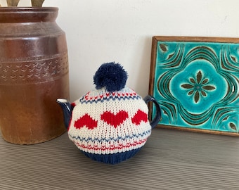 Bule de cerâmica doce de duas xícaras com chá de malha vermelho, branco e azul aconchegante