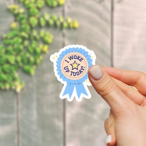 Puede incluir: Una pegatina azul y amarilla con una estrella y el texto "Me desperté hoy".