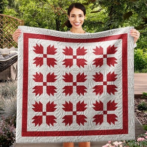 Pode incluir: Um edredom vermelho e branco com um padrão de folhas. O edredom é feito de tecido de algodão e tem uma borda vermelha.