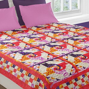 May include: A colourful quilt with a geometric pattern in shades of red, orange, yellow, purple, and white. The quilt is made with a variety of fabrics and has a quilted texture.
