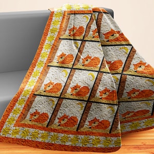 May include: A white, orange, and yellow quilted throw blanket with a repeating pattern of foxes sleeping in a window frame. The blanket has a decorative border with a sun and moon design.