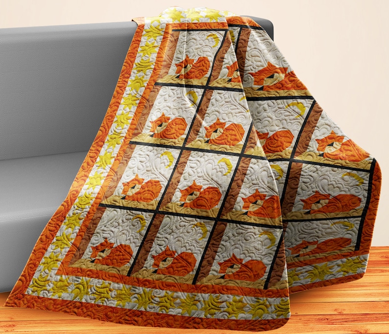May include: A white, orange and yellow quilted throw blanket with a repeating pattern of foxes sleeping in a window frame. The blanket has a decorative border with a sun and moon design.