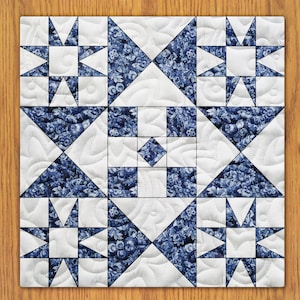 May include: A white quilt with a blue and white patterned design. The quilt is made up of nine squares, each with a different design. The center square is a simple white square, while the other squares feature a variety of geometric patterns.
