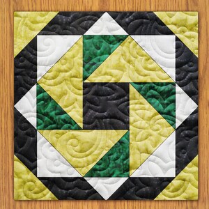 May include: A quilt block with a geometric design featuring black, white, green, and yellow fabric. The block is made up of triangles and squares, and the fabric has a swirl pattern.