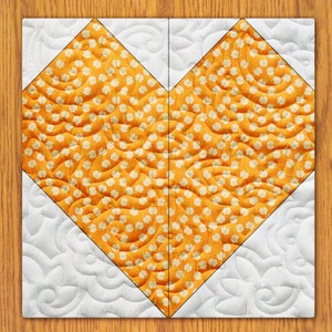 May include: A white and orange heart-shaped quilt with a floral pattern. The quilt is made of fabric squares sewn together to create a heart shape.