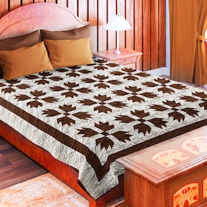 Può includere: Un piumone marrone e bianco con un motivo geometrico. Il piumone è su un letto con una testiera in legno e un piede a letto in legno. Il letto è in una stanza con pareti in legno e un pavimento in legno.