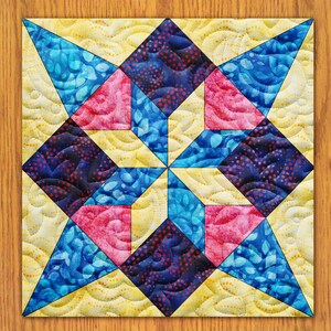 May include: A quilt block with a star design in shades of blue, pink, and yellow. The star is made up of smaller triangles and squares, and the background is a light yellow with a wavy pattern.