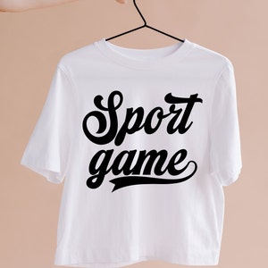 May include: White t-shirt with black text that reads "Sport game" in a retro font.