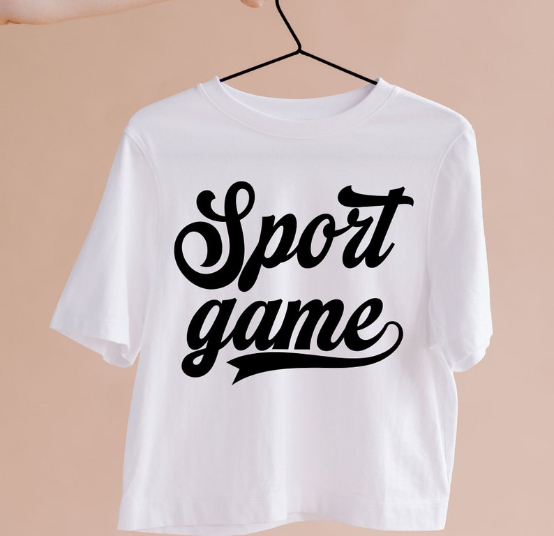 May include: White t-shirt with black text that reads "Sport game" in a retro font.