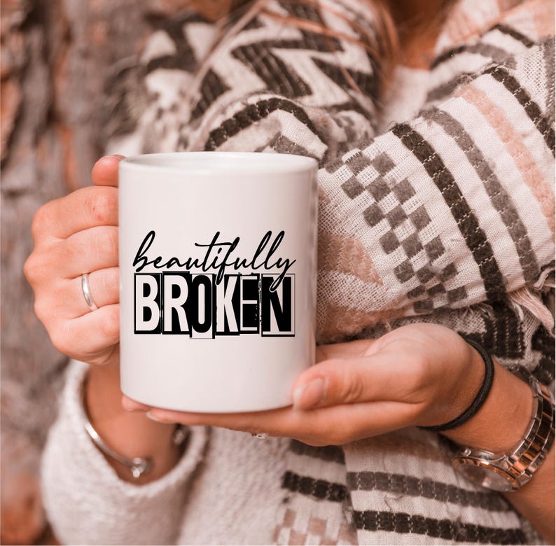 Pu&ograve; includere: Una tazza in ceramica bianca con testo nero che recita "beautifully broken".