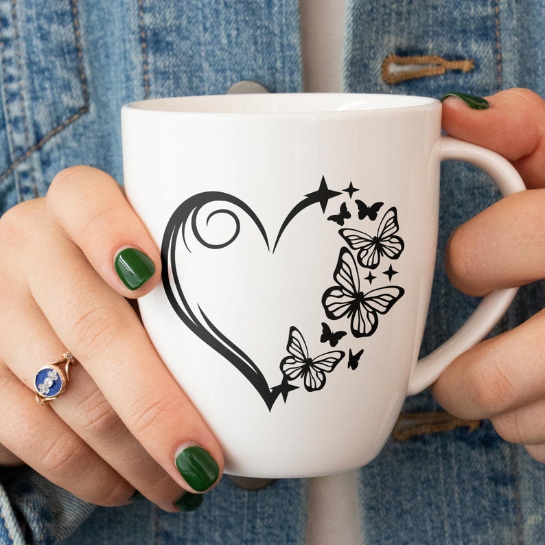 May include: White ceramic mug with a black silhouette of a heart and butterflies. The heart has a swirl design and the butterflies are arranged around the heart.