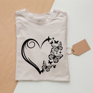 May include: A white t-shirt with a black design of a heart with butterflies and stars.