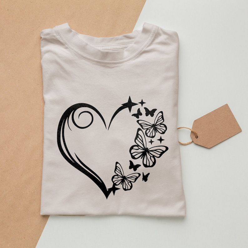 May include: A white t-shirt with a black design of a heart with butterflies and stars.