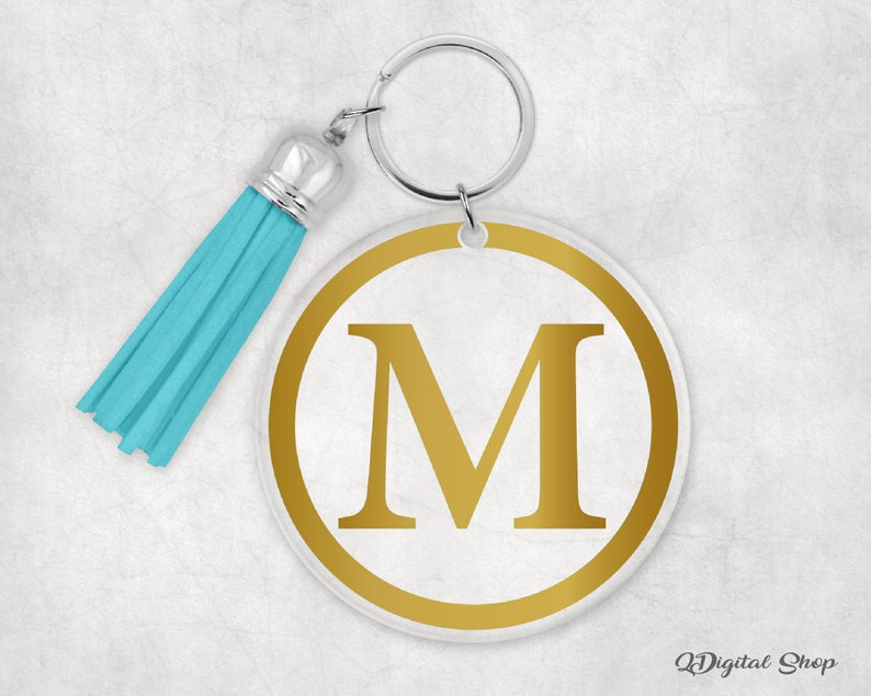 May include: A gold letter M keychain with a turquoise tassel. The letter is on a white circle with a gold outline.