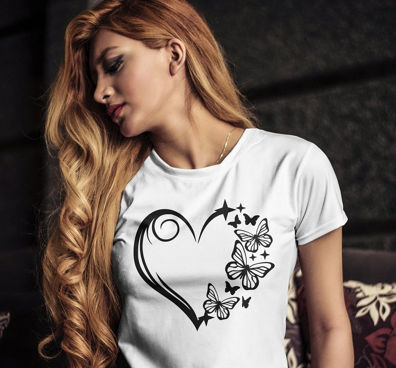 May include: A white t-shirt with a black graphic design of a stylized heart with butterflies and stars.