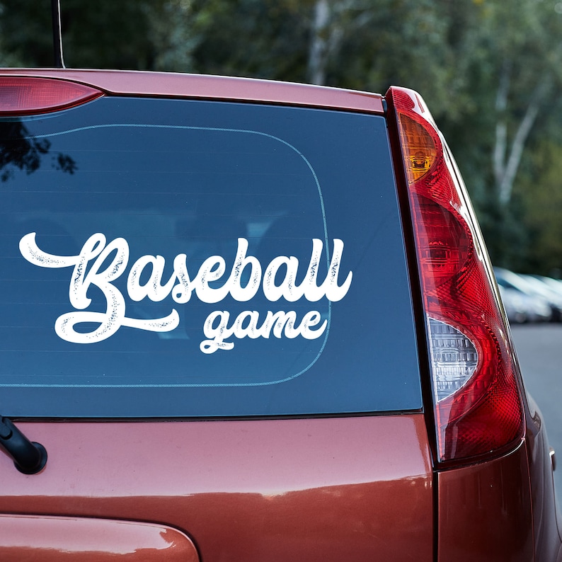 May include: A red car with a white vinyl decal on the back window that says "Baseball game".