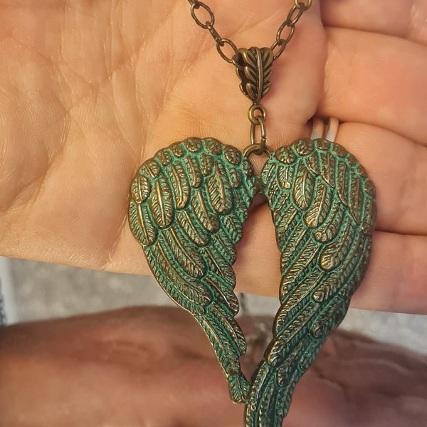 Ali d'angelo in un pendente dal design in ottone con design di perline verdi sulla catena. Ailes d'anges