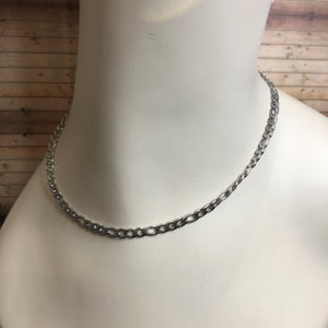 Puede incluir: Un collar de cadena plateado en un maniquí blanco.