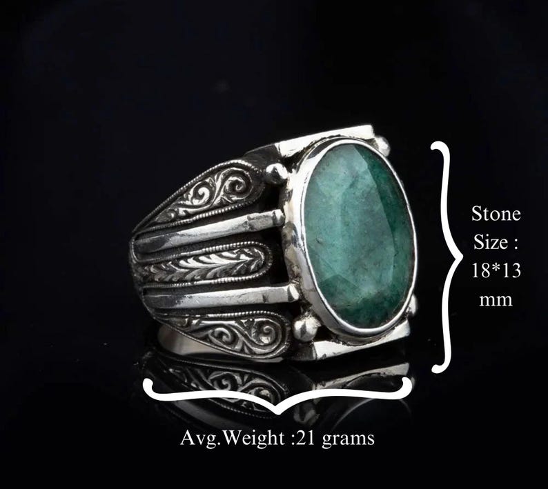 May include: A silver ring with an oval-shaped green gemstone. The ring has intricate floral designs on the band. Stone Size: 18*13 mm. Avg. Weight: 21 grams.