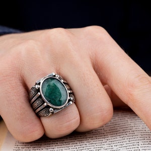 May include: A silver ring with an oval-shaped green gemstone set in a detailed silver band.