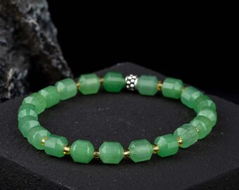 May include: A green gemstone bracelet with silver and gold accents. The bracelet is made of faceted beads and has a simple design.