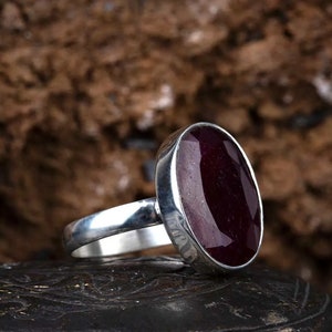 May include: A silver ring with a large, oval-shaped, dark purple gemstone.