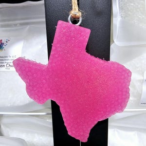 May include: A pink sparkly Texas-shaped car air freshener hanging from a string.