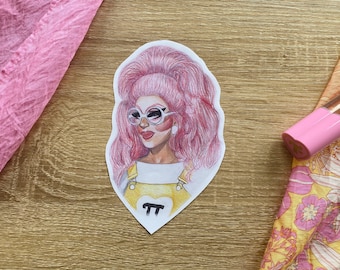Puede incluir: Una ilustración dibujada a mano de una persona con cabello rosado que lleva gafas redondas grandes y un mono amarillo con un corazón y la letra "π" en la parte delantera.