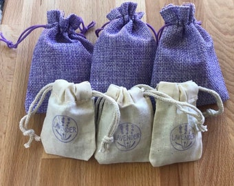 May include: Four small purple burlap bags with drawstrings, each containing a white cotton bag with the word "Lavender" printed in purple. The cotton bags have a drawstring and are filled with lavender.