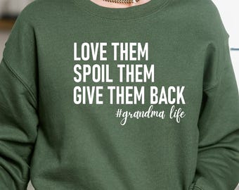 May include: A dark green sweatshirt with the text "LOVE THEM SPOIL THEM GIVE THEM BACK #grandma life" in white. The sweatshirt is a crew neck style and is being worn by a person.