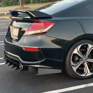 May include: Black Honda Civic Si with a rear spoiler and a black diffuser. The car has a black rear bumper and a black rear window. The car is parked in a car park.